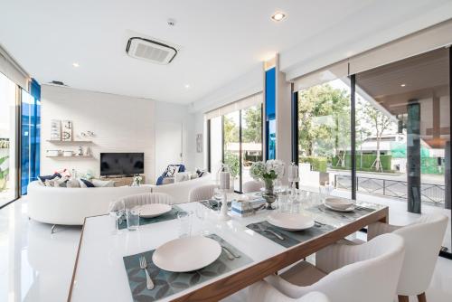 a white living room with a dining table and chairs at Movenpick Residences 3-Bedroom Pool Villa Beach Access, Na Jomtien Pattaya in Na Jomtien