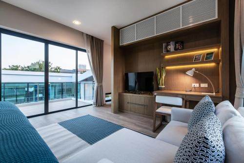 a living room with a couch and a television at Movenpick Residences 3-Bedroom Pool Villa Beach Access, Na Jomtien Pattaya in Na Jomtien