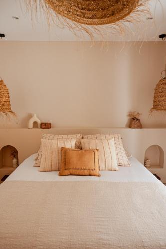 a bedroom with a bed with white sheets and pillows at Lodge des palmiers - jacuzzi in Salazie