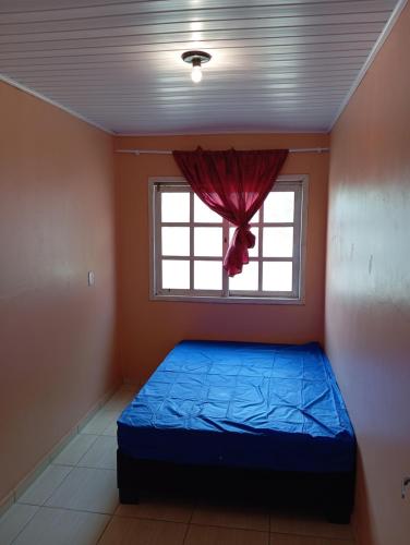 a bedroom with a blue bed and a window at Ampla acomodação e com ótimo localização in Machadinho