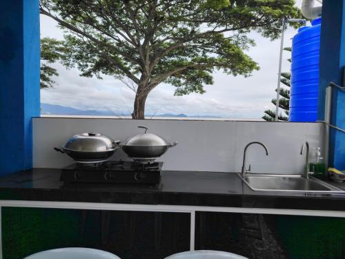 two pans on a stove with a tree in the background at 爱上海蓝蓝屋民宿 Blue Ocean Station in Penampang
