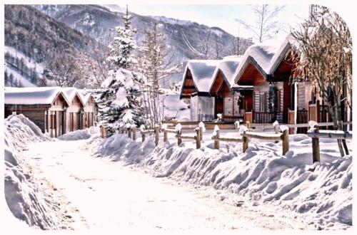 a snow covered house with a fence in front of it at Villaggio Gofree in Pragelato