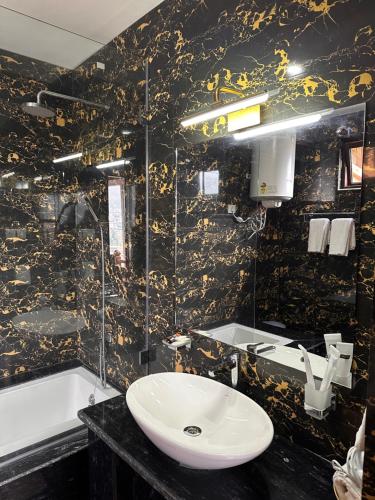 a black and gold bathroom with a sink and a tub at Jambayang Resort in Thimphu