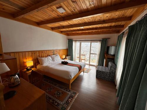 a bedroom with a bed and a large window at Jambayang Resort in Thimphu