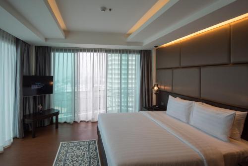 a bedroom with a large bed and a large window at Bay Beach Resort Jomtien in Jomtien Beach