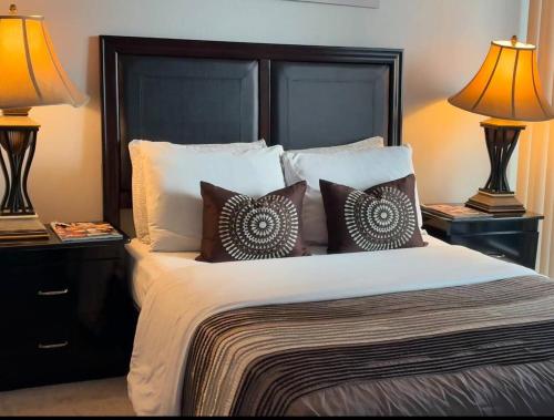 a bedroom with a large bed with pillows and two lamps at Spacious-Cozy 2Bed Condo in Square Ones Misissauga in Mississauga