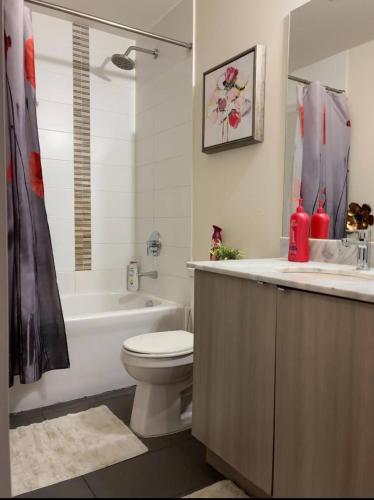 a bathroom with a toilet and a tub and a sink at Spacious-Cozy 2Bed Condo in Square Ones Misissauga in Mississauga