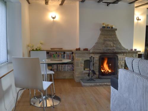 a living room with a fireplace and a table and chairs at Boundary Cottage in Unstone