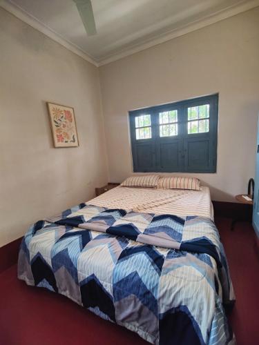 a bedroom with a bed with a blue and white comforter at Classic Jayanagar House for Veg only in Bangalore