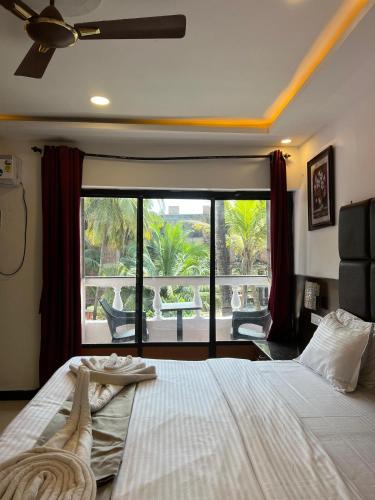 a bedroom with a large bed and a large window at Sportsman beach hotel in Calangute