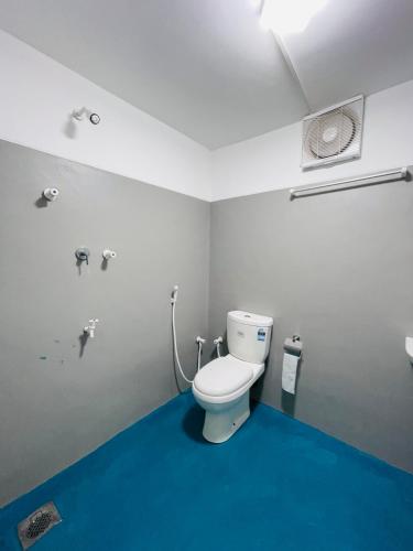 a bathroom with a toilet and a blue floor at Mermaid Hostel in Trincomalee