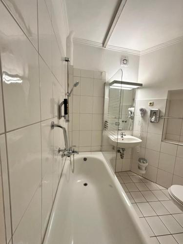 a white bathroom with a tub and a sink at Hotel Marienthal Garni in Hamburg