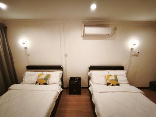 two beds in a room with white sheets and yellow pillows at Pasadena Home in Tawau