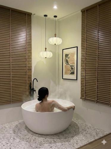 a woman sitting in a bath tub in a bathroom at The Atelier House in Krabi