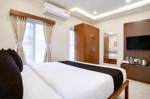 a bedroom with a large white bed and a television at Hotel Rose Inn in Kolkata