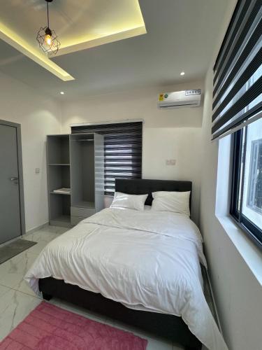 a bedroom with a bed with white sheets and a window at Luxueux duplex 2-bedroom in Ashalebotwe