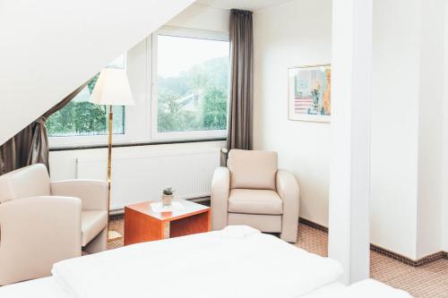 a hotel room with a bed and chairs and a window at Ringhotel Teutoburger Wald in Tecklenburg