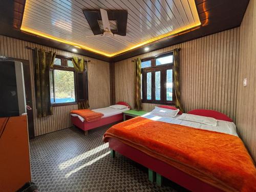 a room with two beds and a tv in it at Gauri Homestay in Pithorāgarh