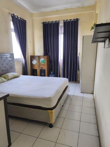 a bedroom with a large bed with purple curtains at Comfy Studio Emerald Hills in Telukjambe