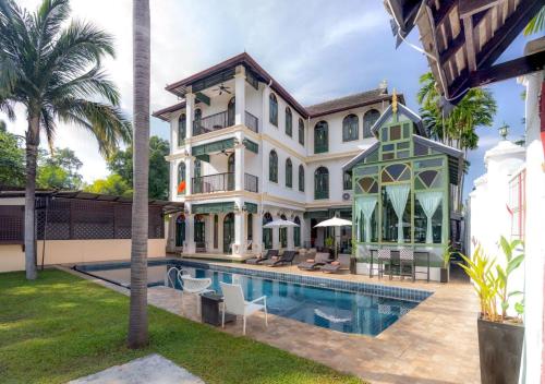 a large mansion with a swimming pool and palm trees at Cheva Gallery Boutique Hotel in Chiang Mai