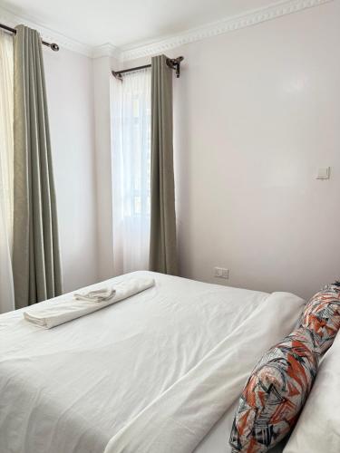 a bed with white sheets and a window in a room at Beytumn Executive Apartment in Ruiru