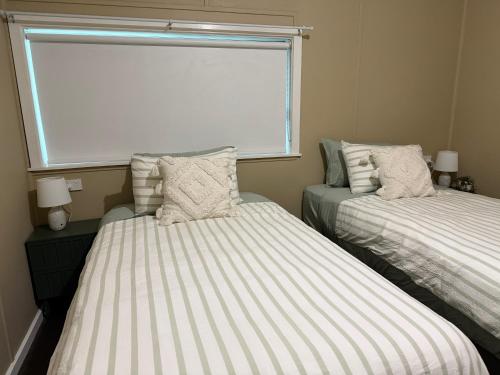 two beds in a small room with a window at Kangaroo Cottage in Hay