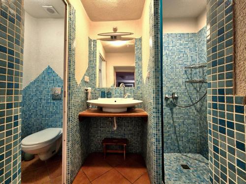 a blue tiled bathroom with a sink and a toilet at Ubytovanie Klinger - chata nad jazerom in Banská Štiavnica
