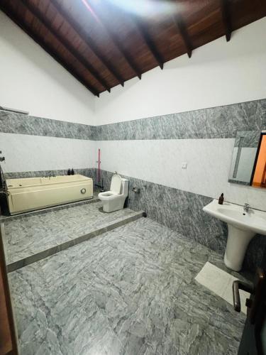a bathroom with a tub and a toilet and a sink at The Green Escape in Miriswatta