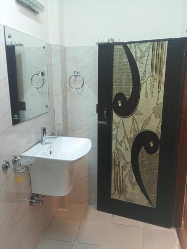 a bathroom with a sink and a shower door at Joyous Rooms in Cherrapunji