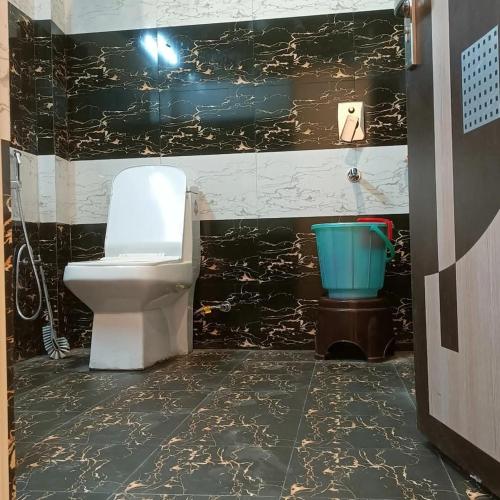 a bathroom with a toilet and a blue bucket at Elite peak hotel in Kasauli