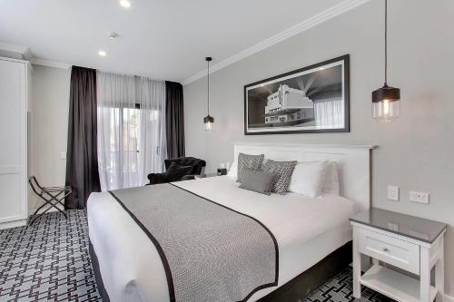 a hotel room with a large bed and a chair at CH Boutique Hotel & Apartments, an Ascend Collection Hotel in Tamworth