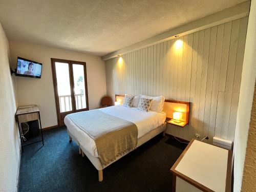 pokój hotelowy z łóżkiem i telewizorem w obiekcie Hôtellerie du Roy w mieście Sainte-Hélène-sur-Isère