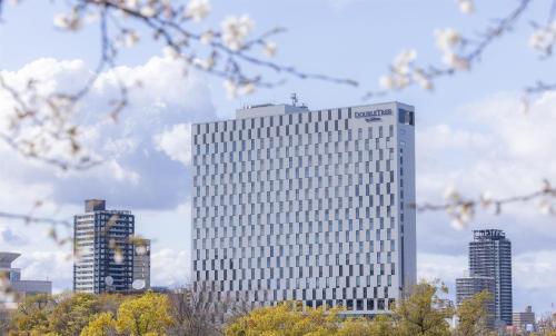 a tall white building in front of some buildings at DoubleTree by Hilton Osaka Castle in Osaka