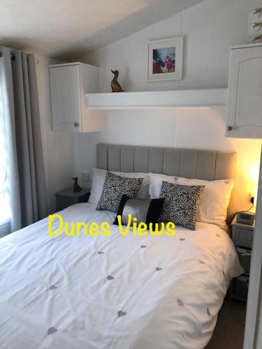 a bedroom with a bed with white sheets and pillows at Dunes Views in Prestatyn