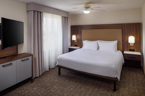 a hotel room with a bed and a flat screen tv at Homewood Suites by Hilton Denver International Airport in Denver