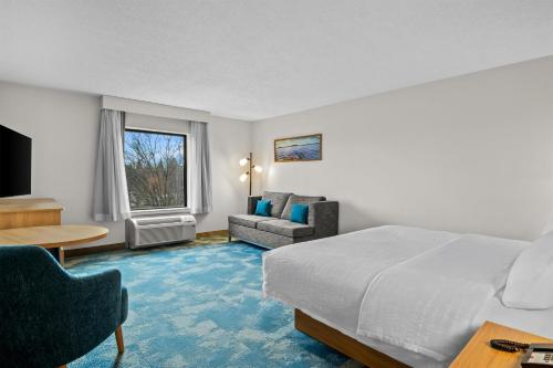 a hotel room with a bed and a couch and a table at Hampton Inn & Suites Detroit-Canton in Canton