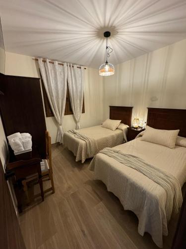 a hotel room with two beds and a chandelier at Los Abuelos Carreros in Consuegra