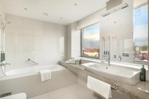a white bathroom with a tub and a sink and a window at DoubleTree By Hilton Košice in Košice