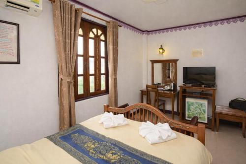 a bedroom with a bed and a window and a tv at Ban Ao Thong in Trang