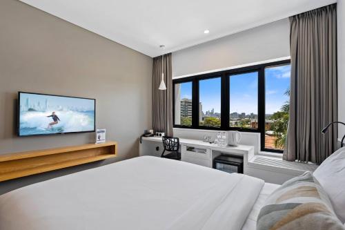 a bedroom with a bed and a tv on a wall at The Kingsford, an Ascend Collection Hotel in Brisbane