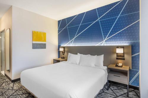 a hotel room with a bed and a blue wall at Comfort Inn Davenport East - Bettendorf in Davenport