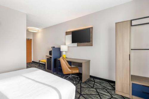 a hotel room with a bed and a desk and a tv at Comfort Inn Davenport East - Bettendorf in Davenport