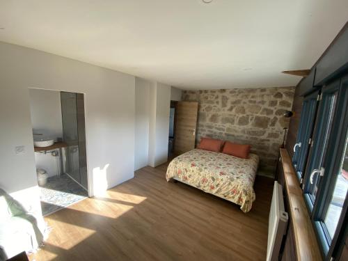 a bedroom with a bed and a stone wall at La Vieille Scierie in Basville