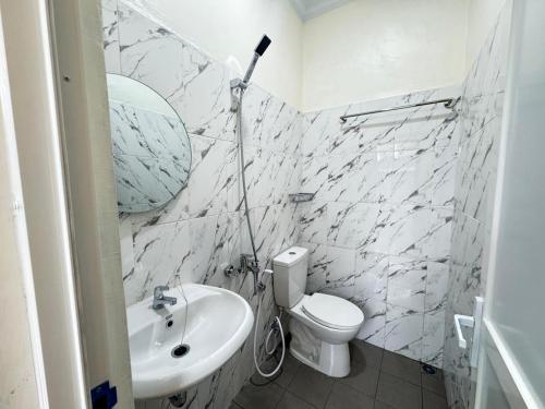 a white bathroom with a sink and a toilet at Kalandra Living in Yogyakarta