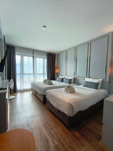 two beds in a hotel room with large windows at The Wing Boutique Hotel in Chiang Mai