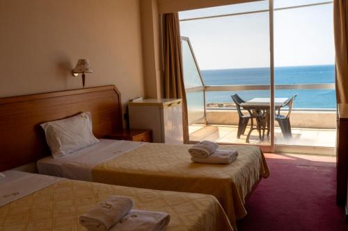 a hotel room with two beds and a view of the ocean at Cavo D' Oro in Piraeus