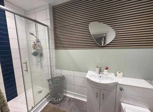 a bathroom with a shower and a sink and a mirror at Spacious 3-Bed Terrace, Great Links in Stowmarket