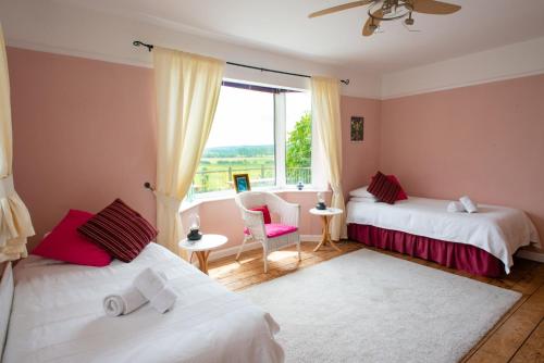 a bedroom with two beds and a window and a chair at Healing Waters Sanctuary, Peaceful Retreat House, Glastonbury in Glastonbury