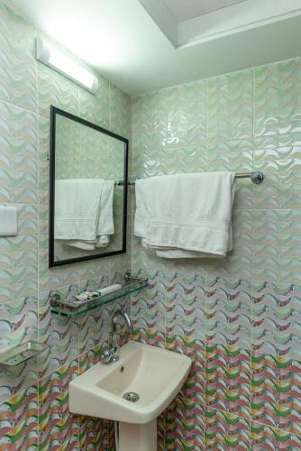 a bathroom with a sink and a mirror and towels at Hotel Tawhid in Rangpur