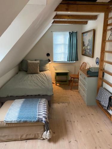 a attic bedroom with a bed and a desk at Pilemosegaard, lejlighed med 2 værelser in Roskilde